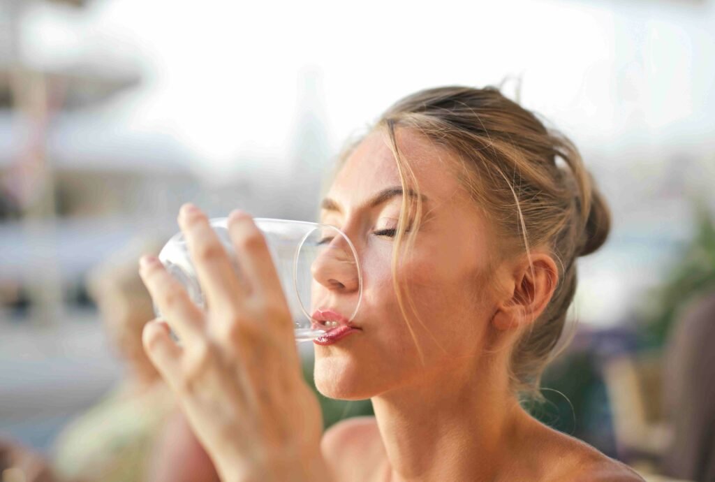 A woman drinking water with aligners on.